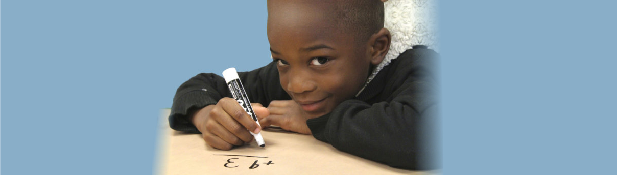 boy writing on a paper while smiling